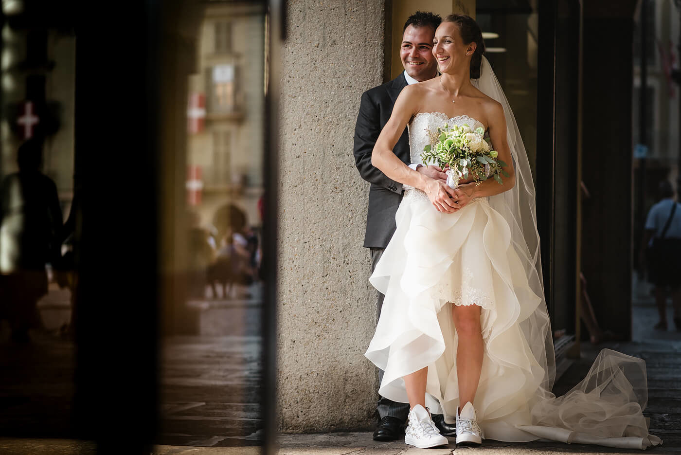 Fotografo di matrimonio Asti sposi sorridenti sotto i portici di Piazza San Secondo