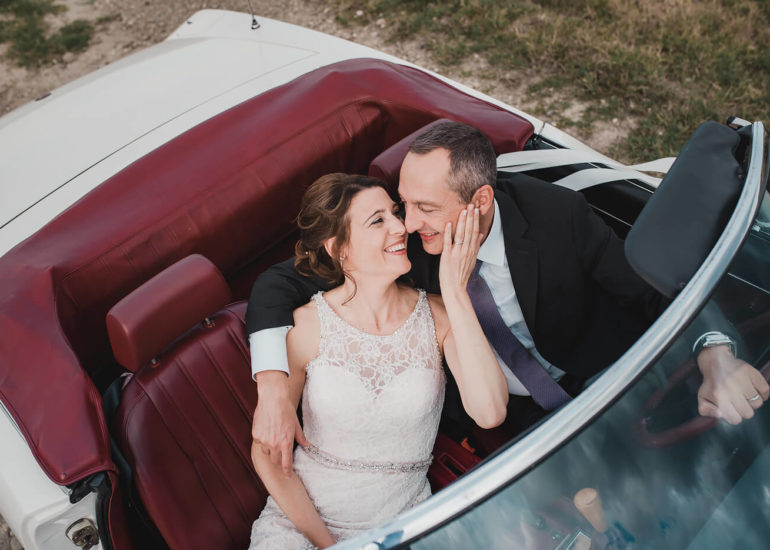 Fotografo di matrimonio Asti sposi che si abbracciano in una fiat spider cabriolet sulle colline di Zonin a Calliano